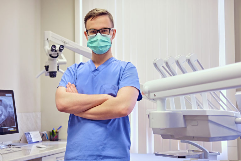 male dentist in a room with medical equipment on background
